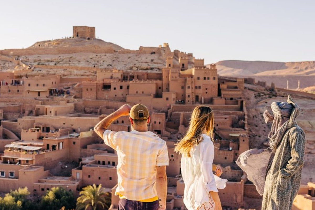 Reisende vor dem Ksar Ait Ben Haddou mit dem Speicher auf dem Hügel, Marokko
